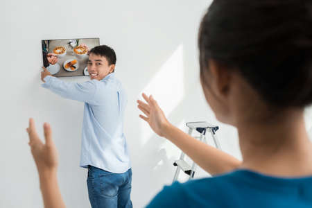 Couple hanging photo on the wall: new apartment decorationの写真素材