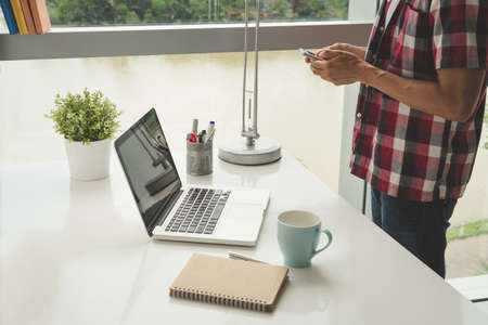 Cropped image of man standing at his table and textingの写真素材
