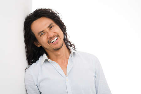 Attractive man with long curly hair smiling and looking at the cameraの写真素材