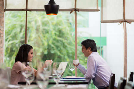 Business couple drinking coffee and discussing ideas in a cafeの写真素材