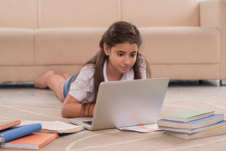 Preteen girl lying on the floor and using laptop