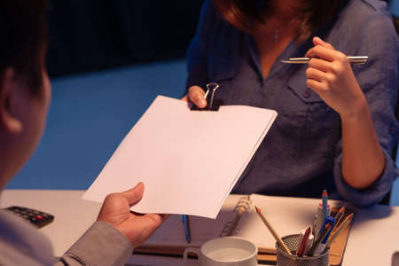 Cropped image of business lady passing papers to her colleagueの写真素材