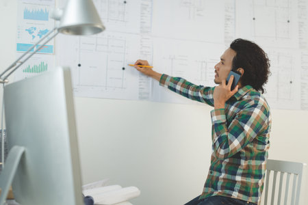 Engineer talking on the phone and making notes on the blueprint