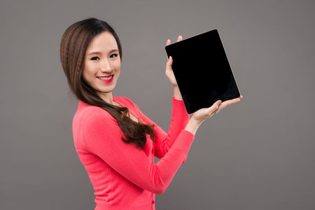 Smiling young Asian woman showing tablet computerの写真素材