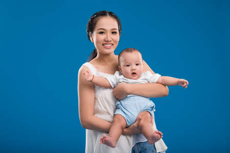 Portrait of beautiful Vietnamese woman carrying cute little boyの写真素材
