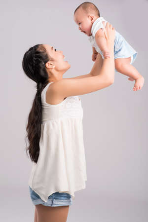 Happy young mother lifting her adorable little sonの写真素材
