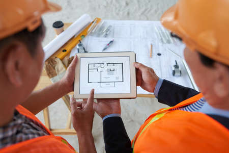 Engineers working with blueprint on tablet computer, view from aboveの写真素材