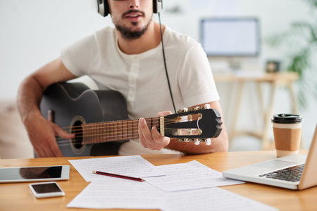 Cropped image of musician playing guitar and writing musicの写真素材