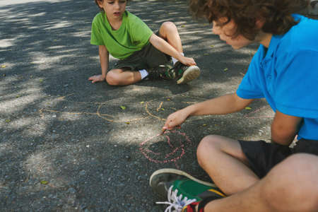 Children drawing on asphalt with colorful chalkの写真素材