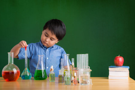 Concentrated little boy adding reagent to the flaskの写真素材