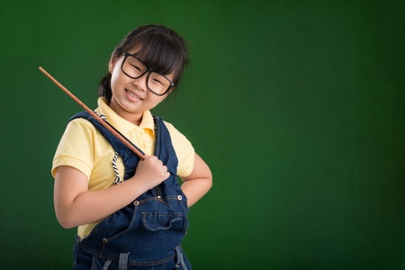 Cute smiling Vietnamese schoolgirl with a pointer, isolated on greenの写真素材