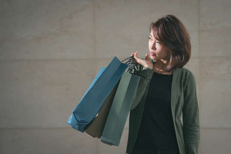 Portrait of Asian young girl carrying shopping bags and looking asideの写真素材