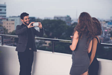 Man taking photo of two young women with a smartphoneの写真素材
