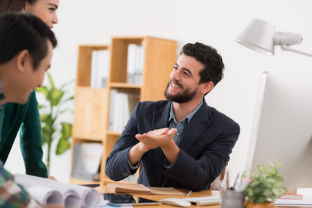 Handsome cheerful businessman talking to his colleaguesの写真素材