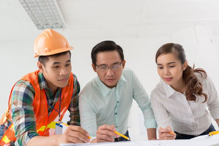 Architects and contractor discussing blueprint of the building