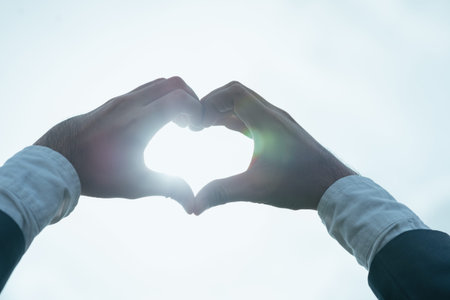 Male hands making heart shape in the sky