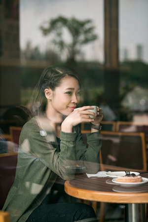 Smiling Vietnamese woman enjoying cup of coffee in the cafeの写真素材