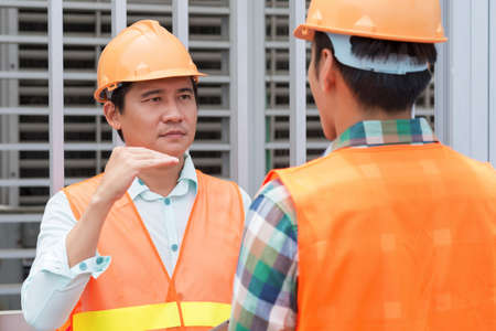 Foreman explaining something to his employee at the construction siteの写真素材