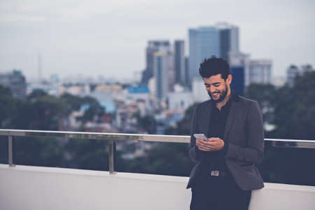 Handsome smiling man reading text message on his smartphoneの写真素材