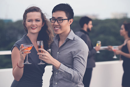 Joyful multi-ethnic couple drinking cocktails at the party