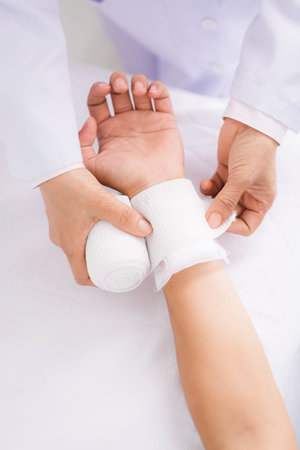 Nurse making bandage to patient who has wrist dislocation