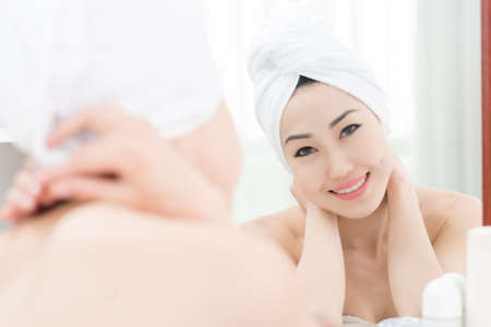 Attractive Asian woman looking at the mirror in her bathroomの写真素材