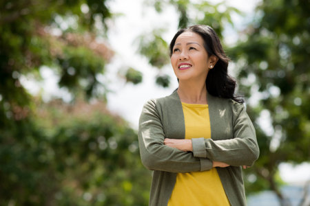 Mature Vietnamese woman enjoying sunny day in the parkの写真素材