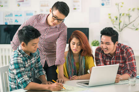 Vietnamese young man sharing his ideas with colleaguesの写真素材