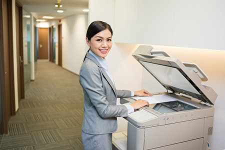 Beautiful Asian secretary using copy machine in the officeの写真素材