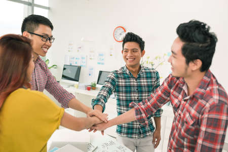 Cheerful coworkers with hands in stack: successful teamwork conceptの写真素材
