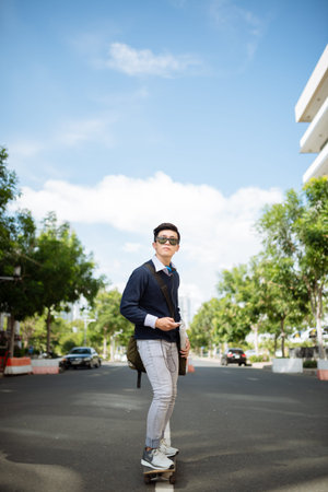 Young man using smartphone while skateboarding in the streetの写真素材
