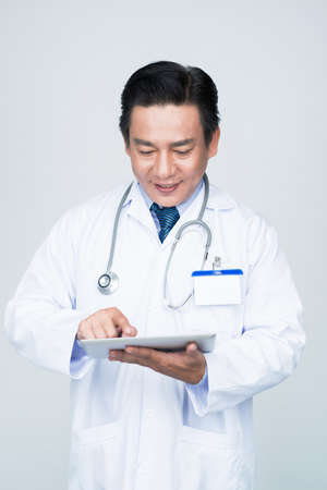 Smiling doctor using application on his tablet computerの写真素材