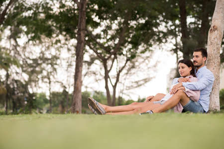 Boyfriend and girlfriend relaxing under the tree in the parkの写真素材