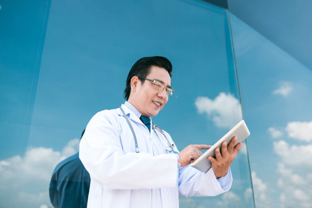Smiling Vietnamese medical worker using digital tabletの写真素材