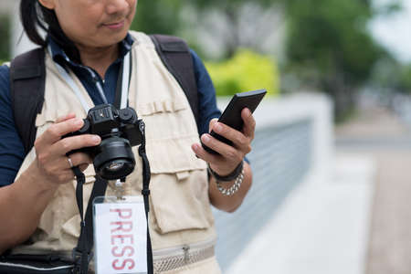 Cropped image of press photographer text messagingの写真素材