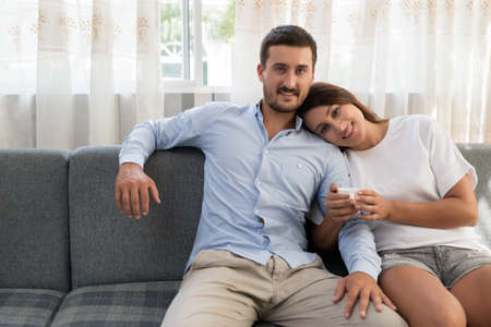 Portrait of relaxed smiling couple sitting on the sofaの写真素材
