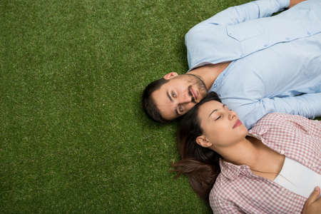 Beautiful young couple lying on the grass, view from aboveの写真素材