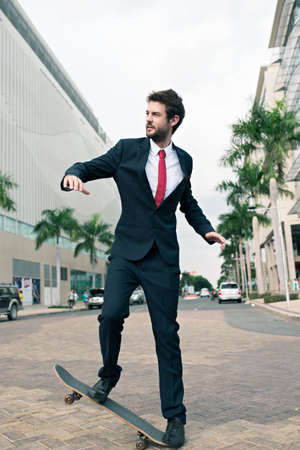 Young stylish businessman skateboarding outdoorsの写真素材