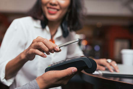 Woman making payment using NFC technology at the shop, cafe or barの写真素材