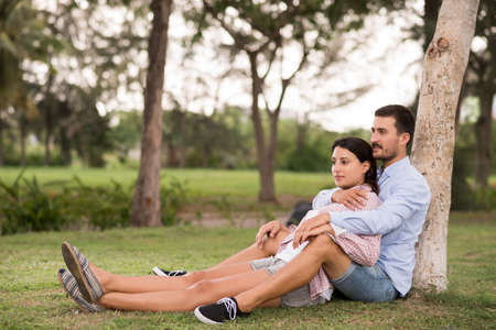 Beautiful serene couple sitting under the treeの写真素材