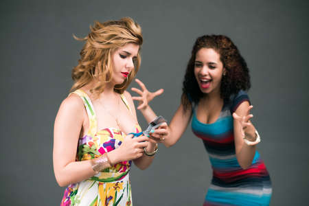 Woman cutting her credit card to the consternation of her friendの写真素材