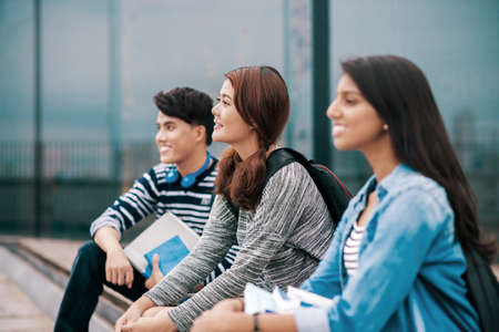 Three high school students sitting together outdoorsの写真素材
