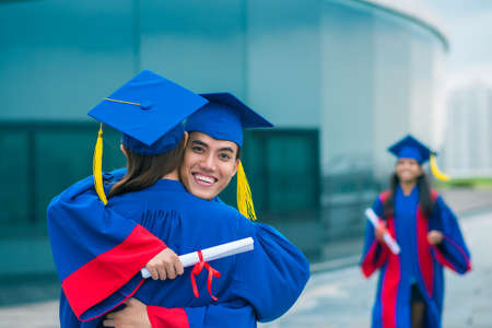 Happy graduates hugging and smiling at cameraの写真素材