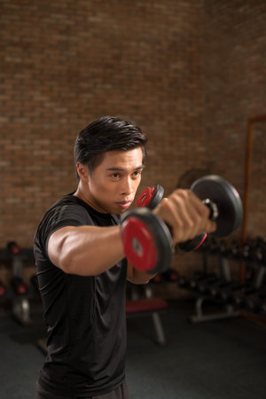 Purposeful man doing exercises with weights