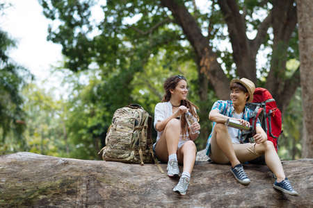 Multiethnic young couple of hikers resting in summer forestの写真素材