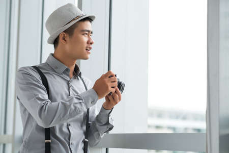 Creative Vietnamese man looking through window to take photoの写真素材