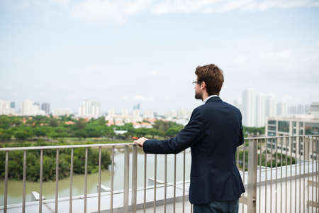 Businessman standing on balcony at looking at the cityの写真素材