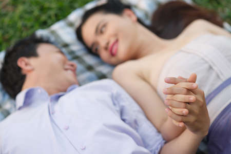 Loving couple lying on plaid holding handsの写真素材