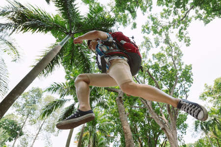 Asian male hiker in a jump, view from belowの写真素材