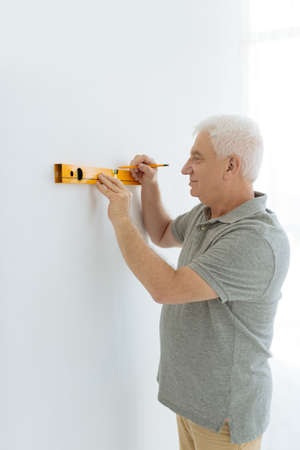 Portrait of senior man measuring walls with levelの写真素材